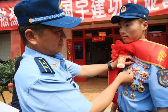 空降兵某旅送喜报小组组长黄辉为周国宇戴上军功章.