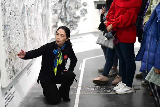 陈少勤在邱志杰的《寰宇全图》展览上,为观众导览作品:世界地图
