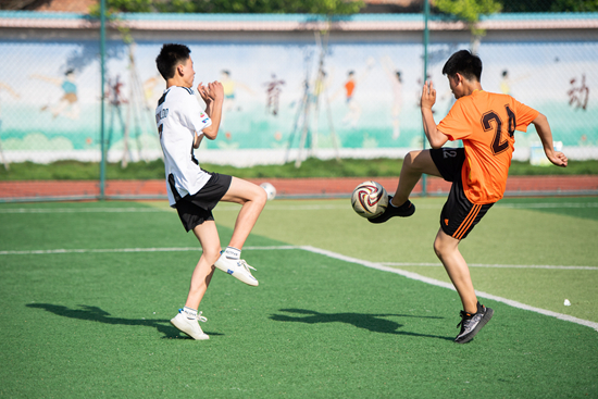 5月12日,学生们在体育课上进行足球训练.